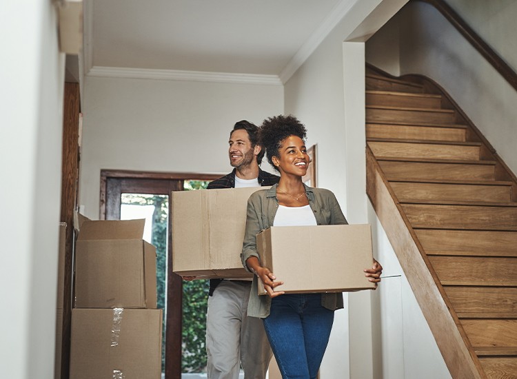 Couple heureux entrant dans leur nouvelle maison avec des boîtes